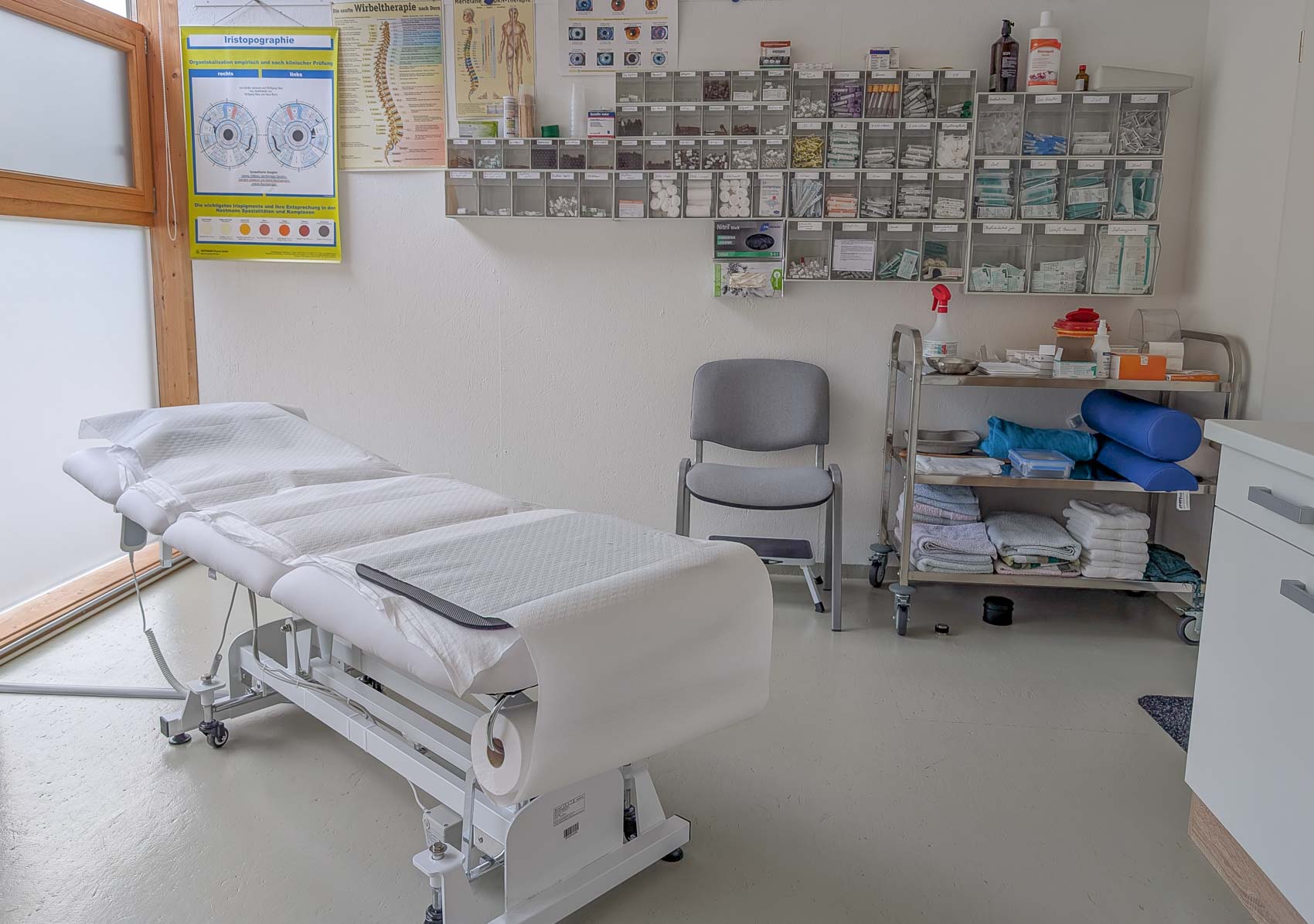 Behandlungsraum mit einer Liege, hellem Tageslicht, beruhigender Dekoration, ruhige und einladende Atmosphäre